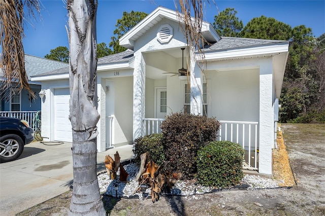 view of front facade featuring stucco siding, a shingled roof, covered porch, an attached garage, and ceiling fan