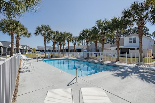 community pool with a residential view, a patio area, and fence