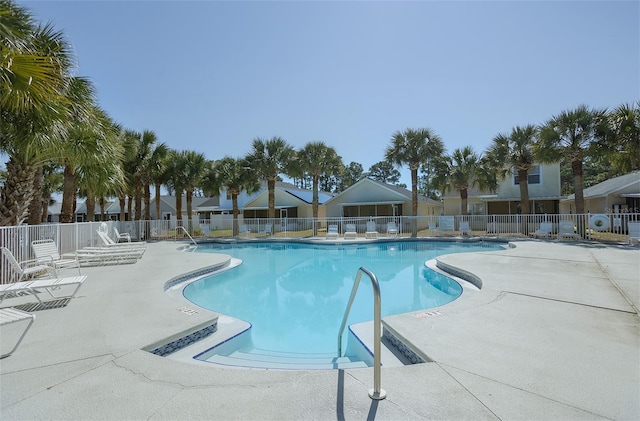 pool with a patio area, fence, and a residential view