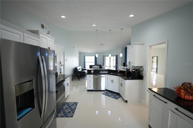14712 Eagles Crossing Dr, Orlando, FL 32837 - kitchen featuring stainless steel appliances, dark countertops, vaulted ceiling, white cabinetry, and a peninsula
