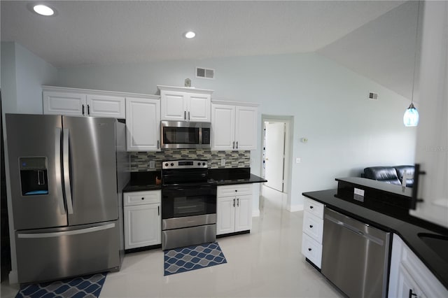14712 Eagles Crossing Dr, Orlando, FL 32837 - kitchen with stainless steel appliances, vaulted ceiling, dark countertops, white cabinets, and decorative backsplash
