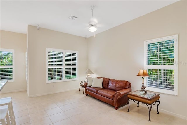 living area featuring a ceiling fan, visible vents, baseboards, and light tile patterned floors