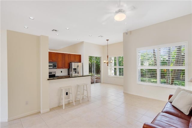 kitchen featuring a breakfast bar area, stainless steel appliances, dark countertops, an inviting chandelier, and open floor plan