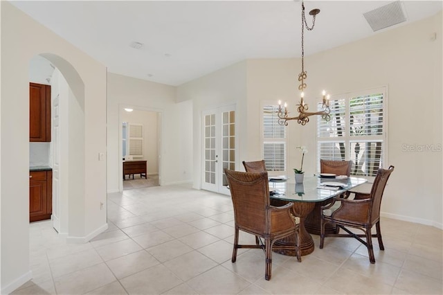 dining area featuring light tile patterned floors, baseboards, visible vents, arched walkways, and french doors