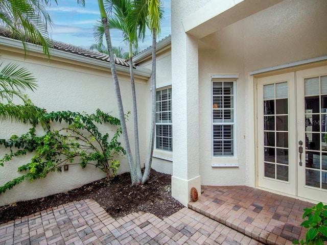 doorway to property featuring french doors, a patio area, and stucco siding