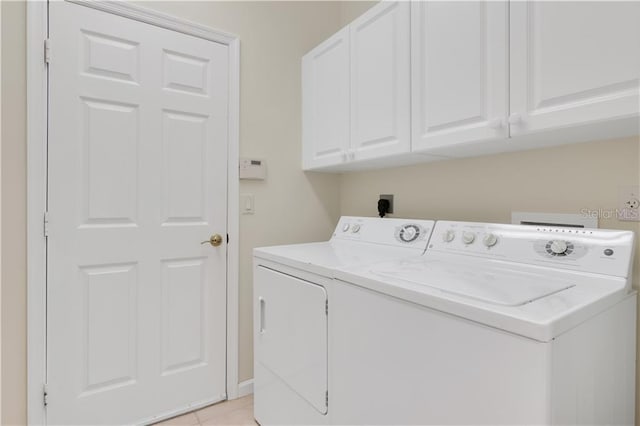 washroom featuring light tile patterned floors, separate washer and dryer, and cabinet space