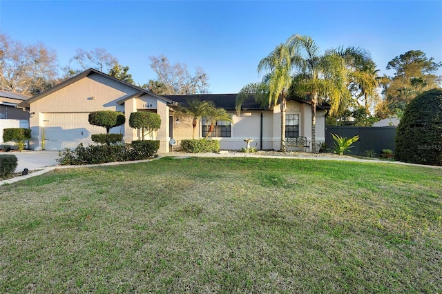 view of front of property with a front lawn, an attached garage, fence, and stucco siding