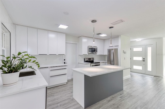 kitchen with visible vents, light wood-style flooring, appliances with stainless steel finishes, light countertops, and white cabinetry