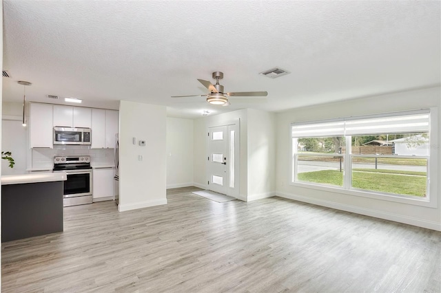 kitchen featuring light wood finished floors, visible vents, appliances with stainless steel finishes, light countertops, and backsplash