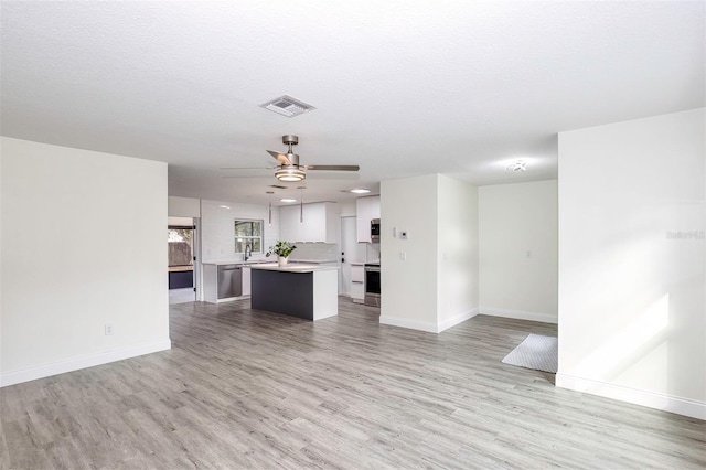 unfurnished living room featuring visible vents, ceiling fan, light wood finished floors, and a sink