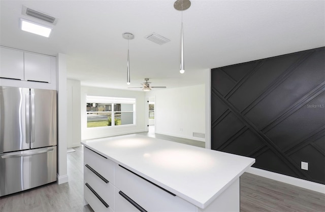 kitchen with light countertops, freestanding refrigerator, white cabinets, and visible vents