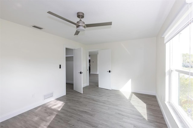 spare room featuring a ceiling fan, baseboards, visible vents, and wood finished floors