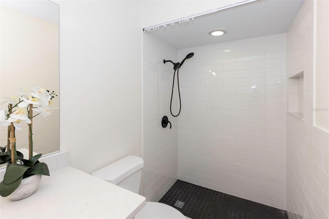 full bathroom featuring vanity, a tile shower, and toilet