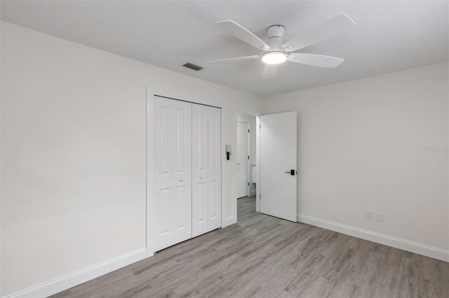 unfurnished bedroom featuring a closet, wood finished floors, visible vents, and baseboards