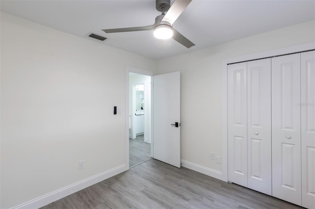 unfurnished bedroom featuring a closet, visible vents, baseboards, and wood finished floors