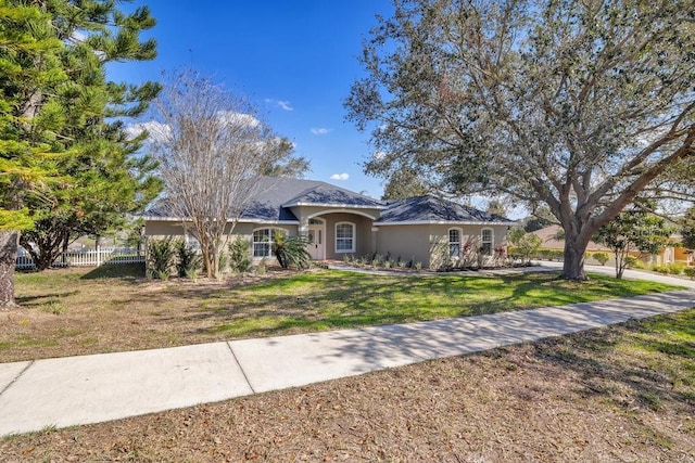 view of front of house with fence, a front lawn, and stucco siding