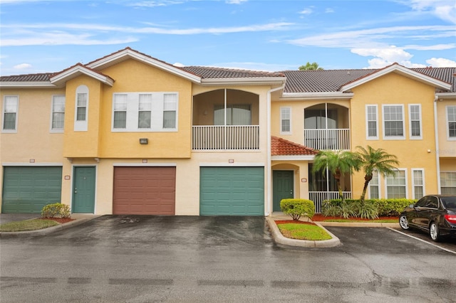 multi unit property with a garage, a tile roof, and stucco siding