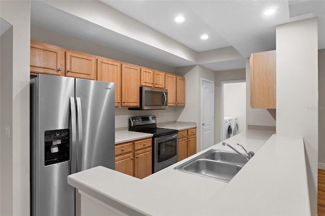 kitchen with recessed lighting, stainless steel appliances, separate washer and dryer, a peninsula, and a sink