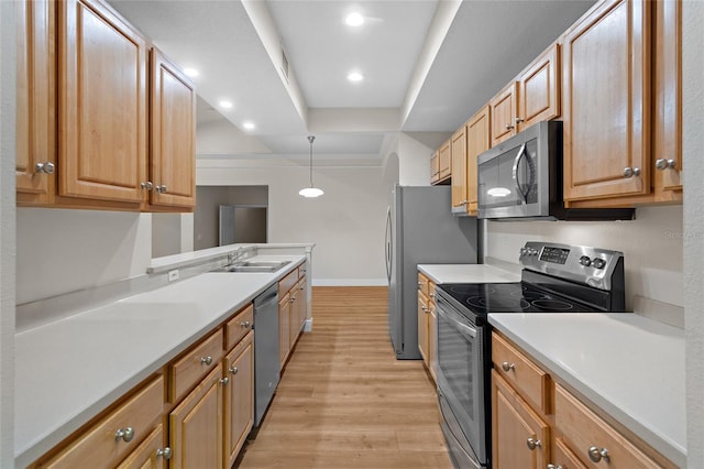 kitchen featuring baseboards, appliances with stainless steel finishes, light countertops, light wood-style floors, and a sink