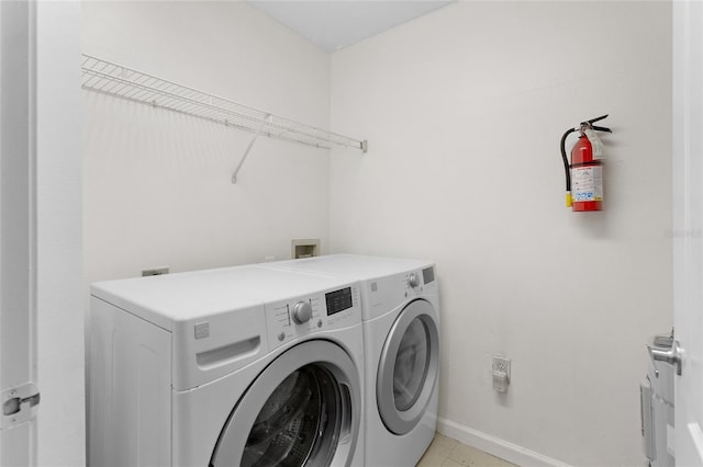 clothes washing area with laundry area, light tile patterned flooring, washer and clothes dryer, and baseboards