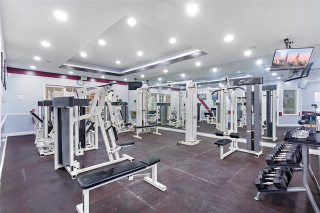 gym featuring recessed lighting, a raised ceiling, and baseboards