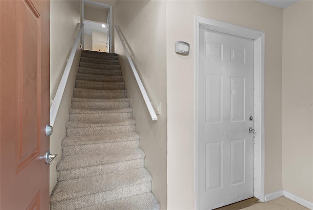 stairs with baseboards and tile patterned floors