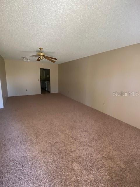 carpeted empty room featuring ceiling fan and a textured ceiling