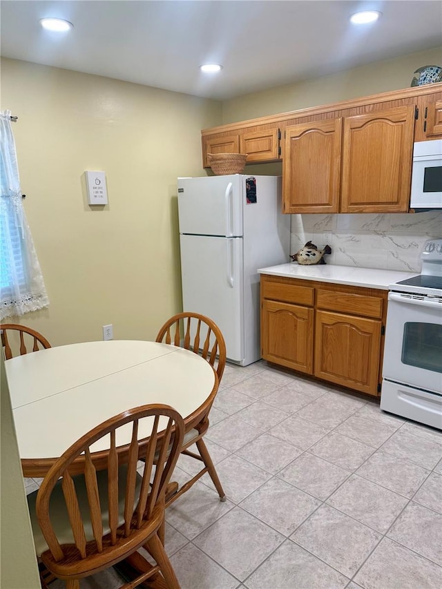 kitchen with brown cabinetry, white appliances, light countertops, and tasteful backsplash