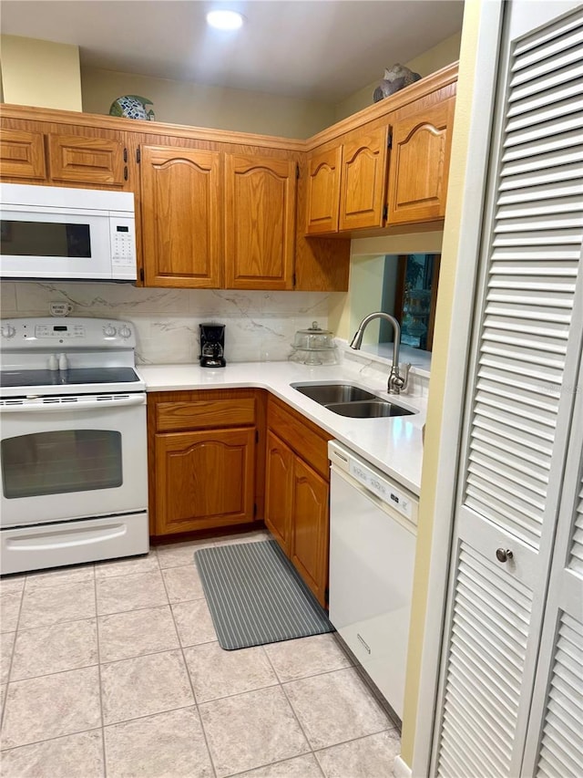 kitchen with light countertops, white appliances, brown cabinetry, and a sink