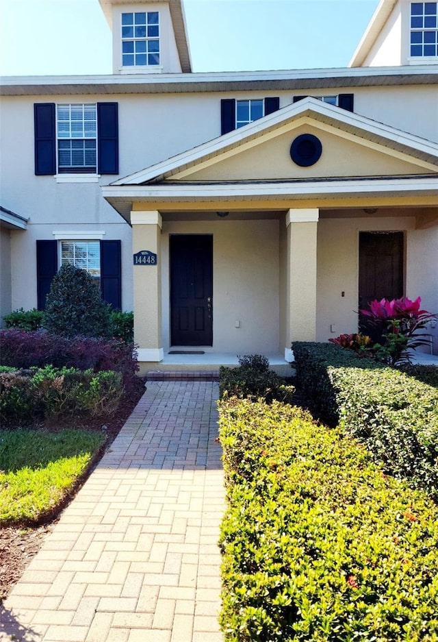 entrance to property with a porch and stucco siding