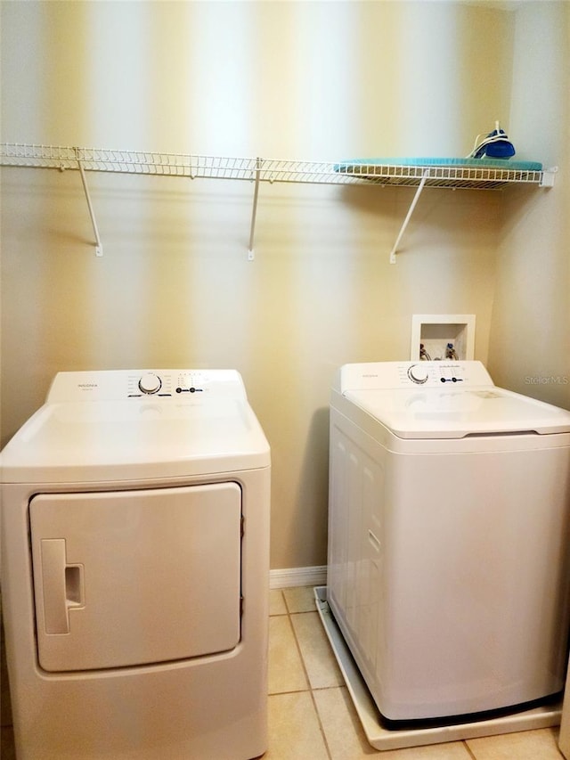 clothes washing area featuring light tile patterned floors, laundry area, baseboards, and washer and dryer