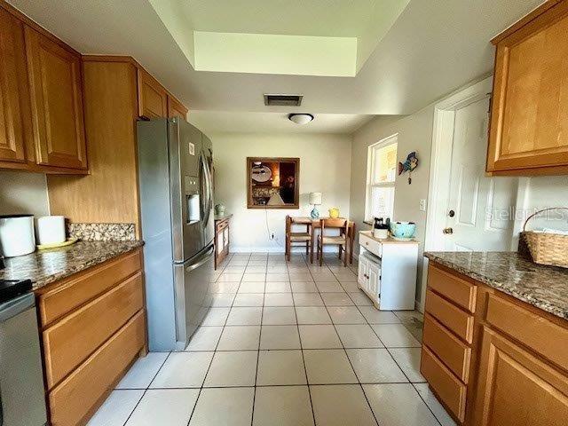 kitchen featuring brown cabinetry, a tray ceiling, and stainless steel refrigerator with ice dispenser