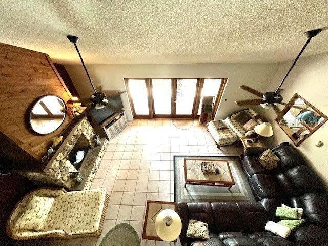 living room with tile patterned flooring, ceiling fan, and a textured ceiling