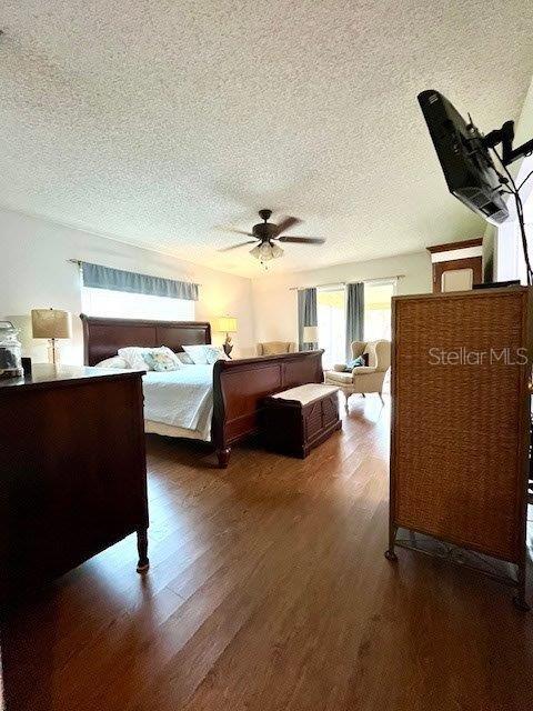 bedroom with ceiling fan, a textured ceiling, and wood finished floors