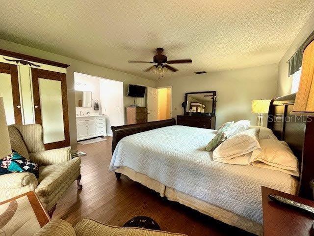 bedroom featuring visible vents, ceiling fan, a textured ceiling, and wood finished floors