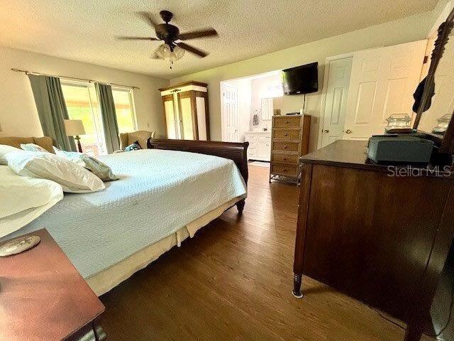 bedroom featuring a ceiling fan, dark wood finished floors, and a textured ceiling