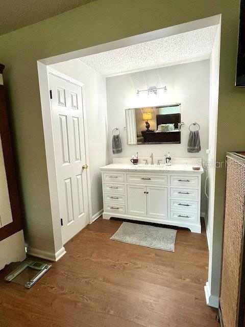 bathroom featuring a textured ceiling, vanity, baseboards, and wood finished floors