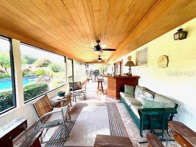 sunroom / solarium featuring a ceiling fan and wooden ceiling