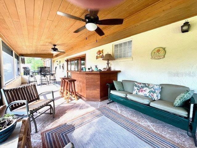 sunroom featuring wood ceiling and a ceiling fan