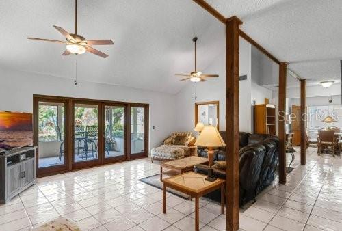 living room with ceiling fan, high vaulted ceiling, french doors, and a textured ceiling