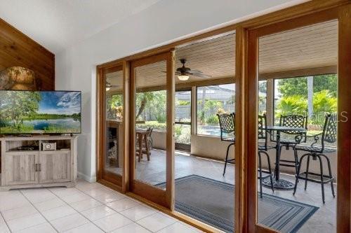 doorway to outside with a ceiling fan, lofted ceiling, and light tile patterned floors