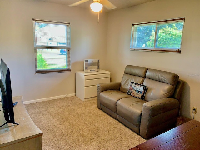 living room with light carpet, a ceiling fan, and baseboards