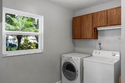 clothes washing area with washing machine and dryer and cabinet space