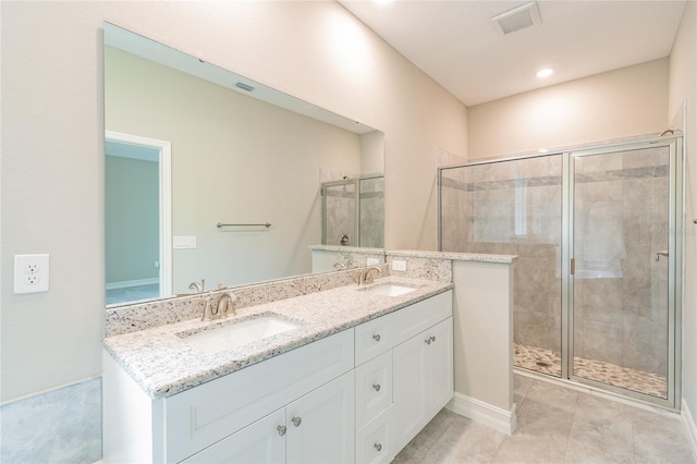 bathroom with double vanity, a shower stall, visible vents, and a sink