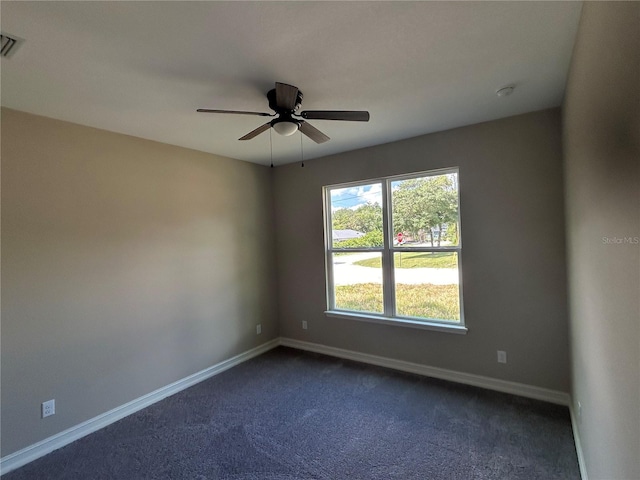 spare room with dark carpet, baseboards, and ceiling fan