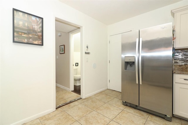 kitchen with light tile patterned floors, white cabinetry, baseboards, and stainless steel fridge with ice dispenser