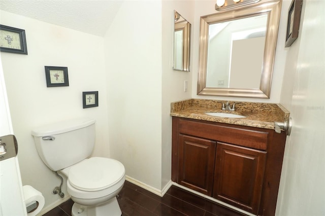 half bathroom with baseboards, toilet, wood finished floors, a textured ceiling, and vanity