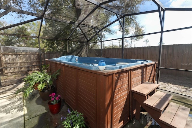 view of patio featuring glass enclosure, a fenced backyard, and a hot tub