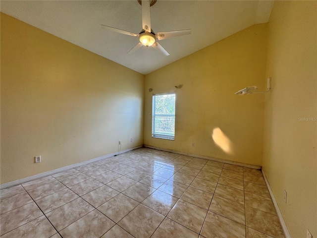 empty room with vaulted ceiling, light tile patterned floors, a ceiling fan, and baseboards