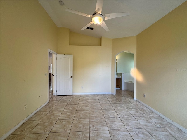 empty room featuring arched walkways, visible vents, a ceiling fan, light tile patterned flooring, and vaulted ceiling